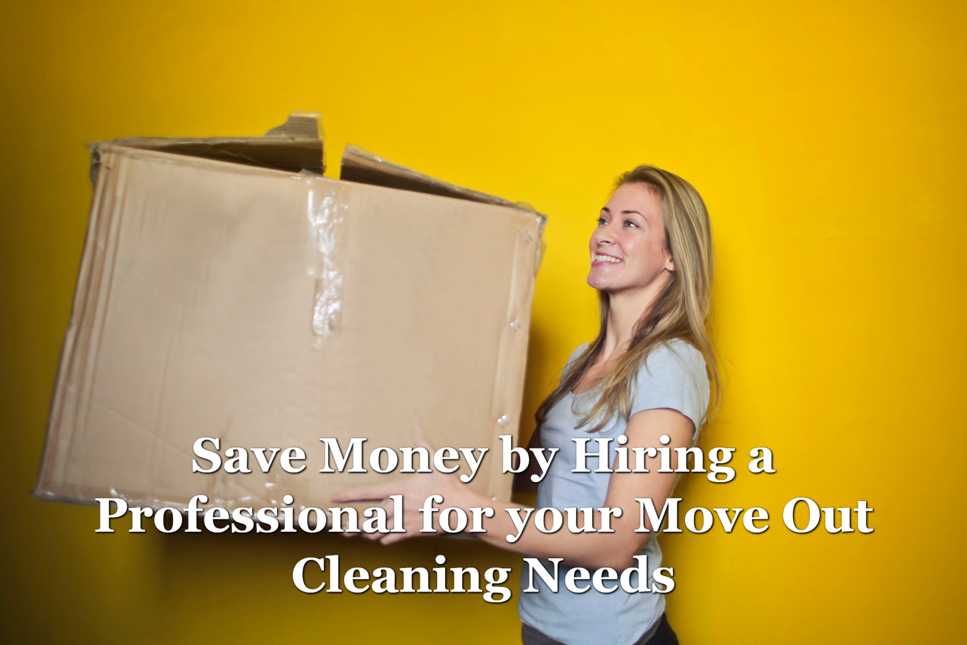 A woman holding a large cardboard box and smiling because she hired someone for her move out cleaning