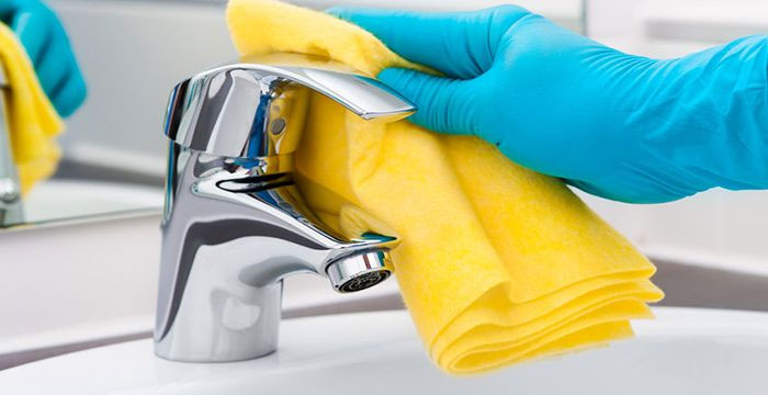 What does a housekeeper do? Cleaning a faucet with gloves on.